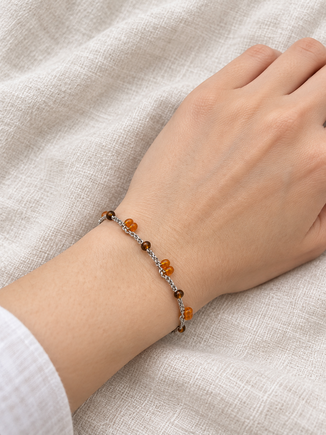 Pulsera Ámbar puesta en la muñeca sobre lino